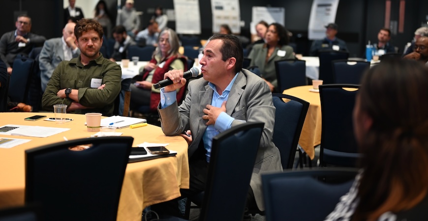 Photo depicts an attendee speaking into a microphone to ask a question at the Rural Energy Summit at UC Merced.