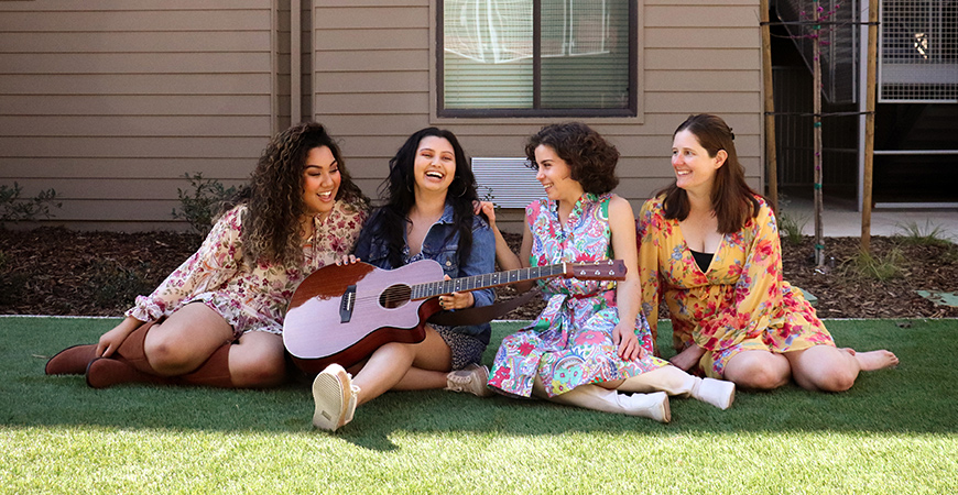 Sofia Andom, Cat Flores, Bella Camfield and Bethy Harmelin are seen sitting on the grass.